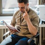 Focused man reading notes in a modern office environment.